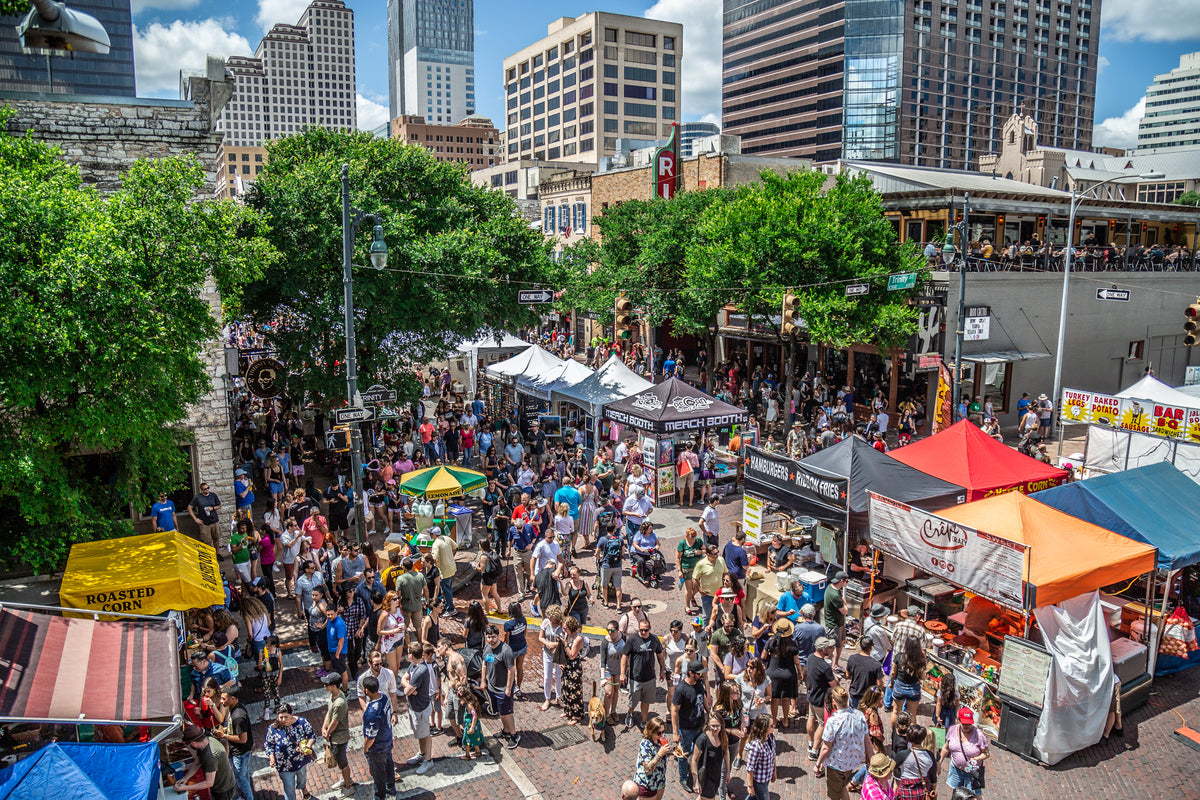 High-angle view of a crowded street festival with colorful vendor tents