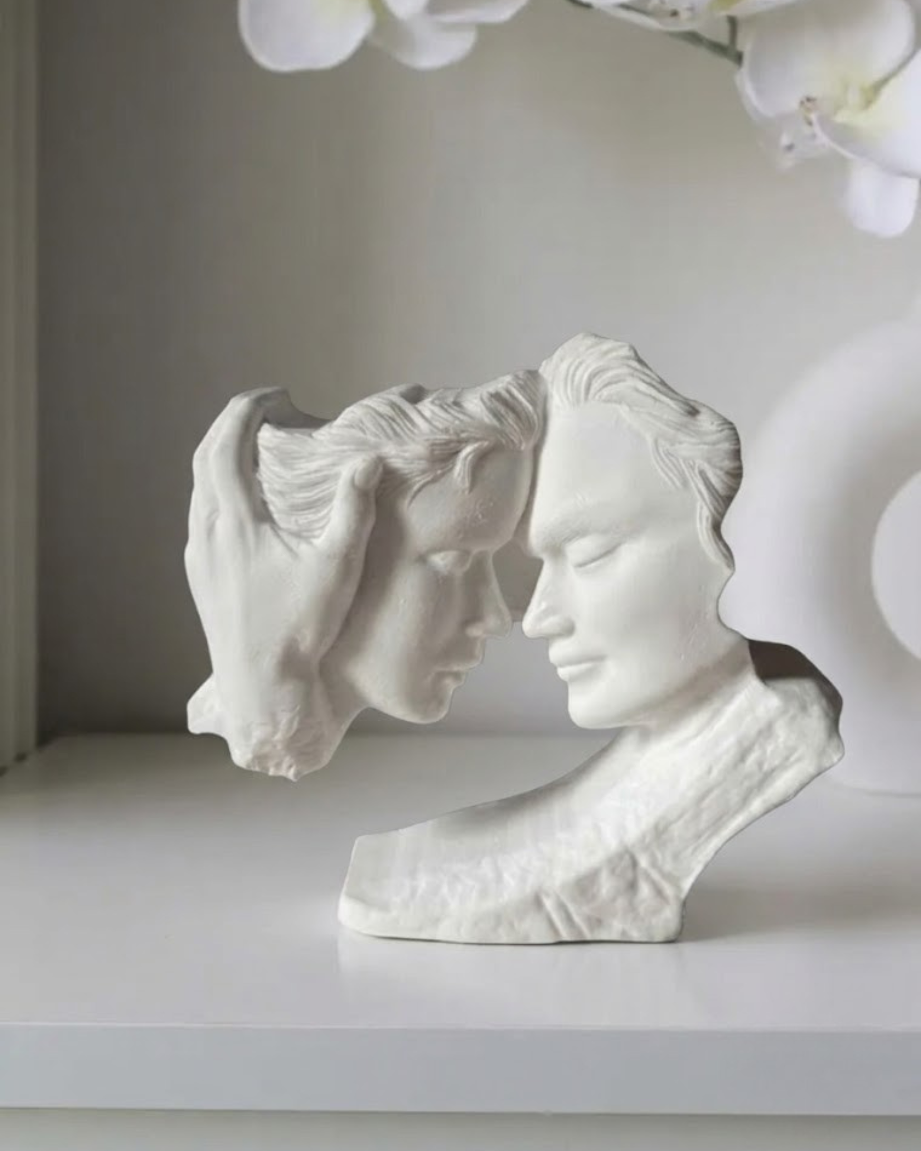 Modern couple sculpture with two faces and a supporting hand