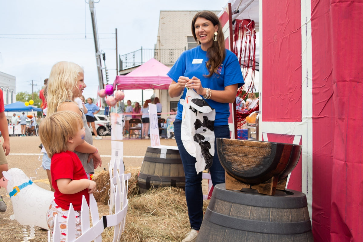 Children playing a farm-themed game at an outdoor carnival booth